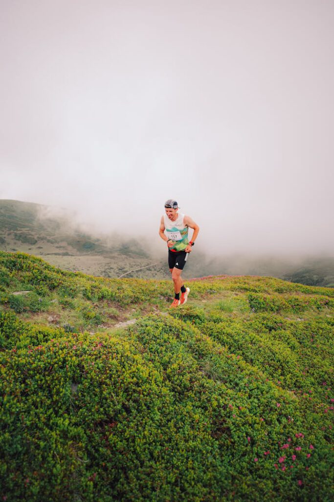 A runner navigating lush green hills under a misty sky, showcasing endurance in nature.